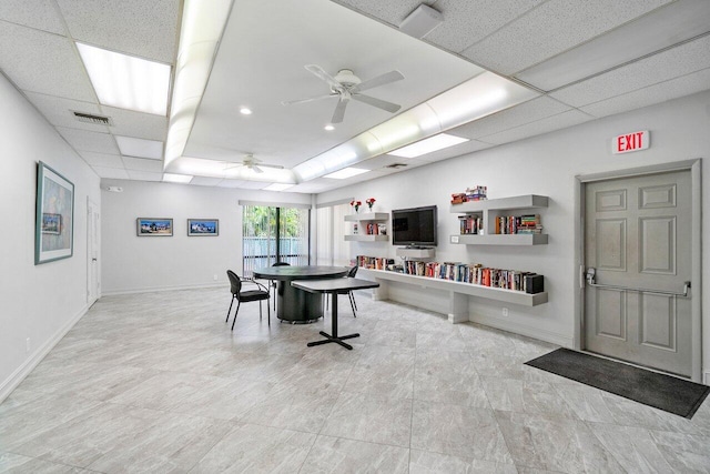 interior space with a paneled ceiling and ceiling fan