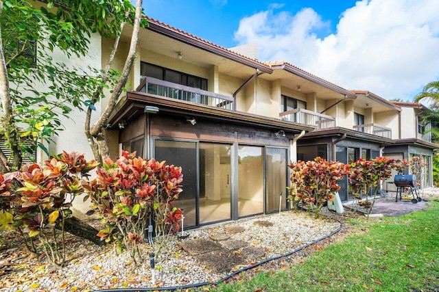 rear view of property with a sunroom and a balcony