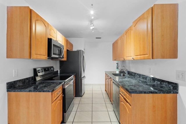 kitchen featuring sink, light tile patterned flooring, dark stone counters, and appliances with stainless steel finishes