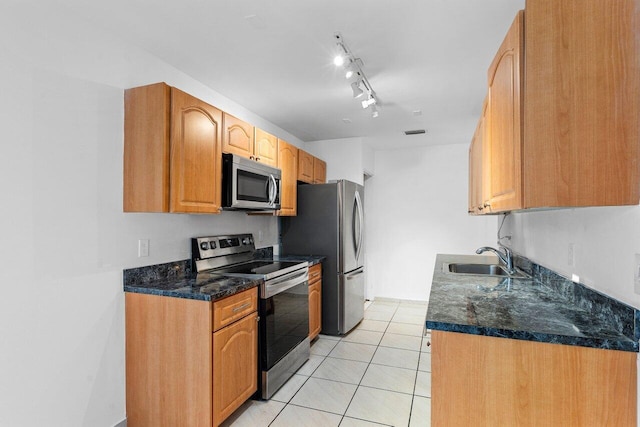 kitchen featuring rail lighting, sink, dark stone countertops, light tile patterned floors, and appliances with stainless steel finishes