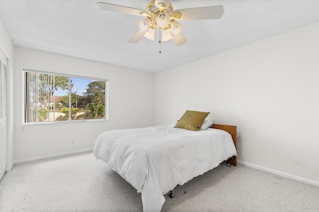 bedroom with ceiling fan, light colored carpet, a textured ceiling, and a closet