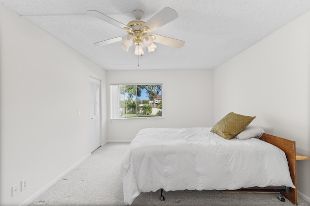 bedroom featuring ceiling fan, light carpet, a textured ceiling, and a closet