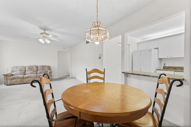 carpeted dining area with a textured ceiling and ceiling fan