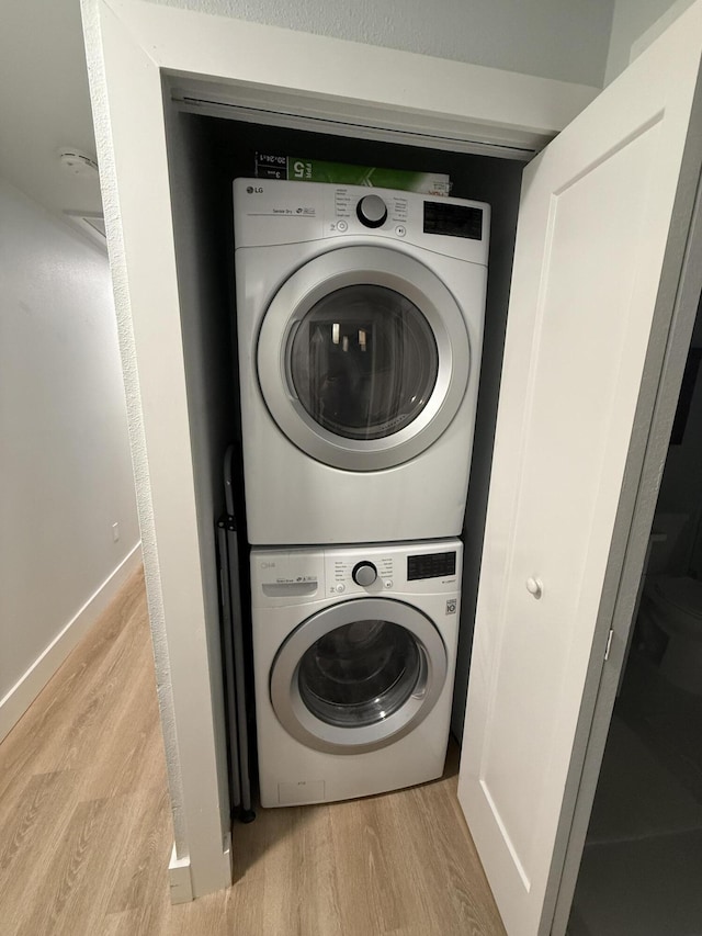 laundry area featuring stacked washer and clothes dryer and light wood-type flooring