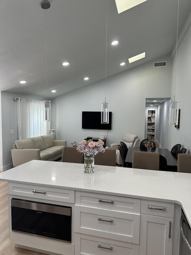 kitchen with white cabinetry, lofted ceiling, dishwasher, and pendant lighting