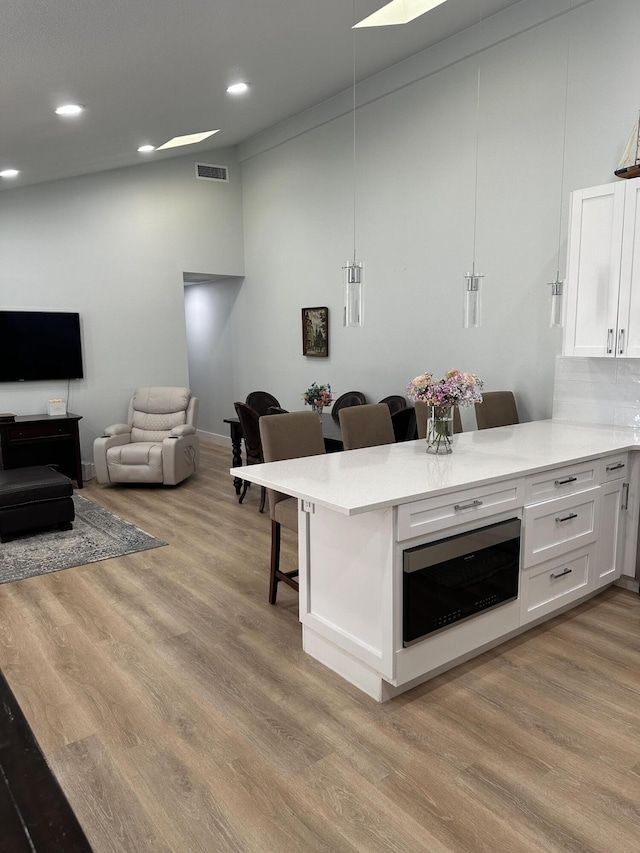 kitchen with pendant lighting, a kitchen breakfast bar, kitchen peninsula, and white cabinets