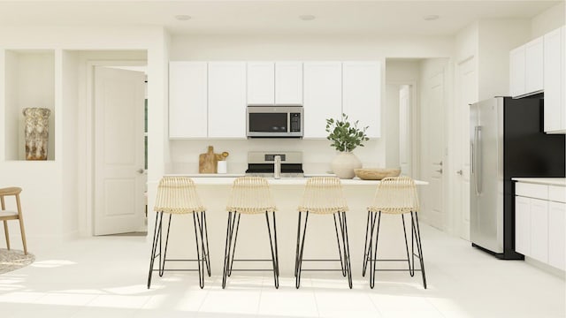 kitchen featuring appliances with stainless steel finishes, a breakfast bar, a kitchen island with sink, and white cabinets