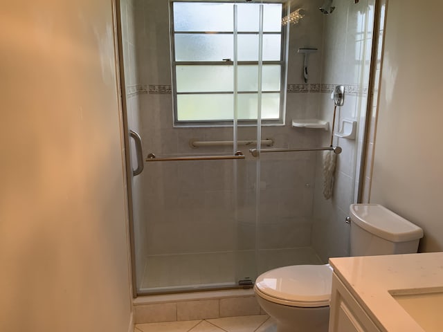 bathroom with vanity, toilet, tile patterned floors, and a shower with shower door