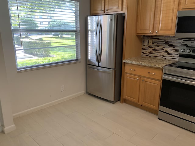 kitchen with appliances with stainless steel finishes, backsplash, and light stone counters