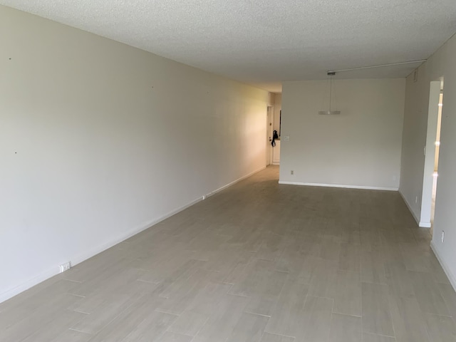 unfurnished room featuring a textured ceiling and light wood-type flooring