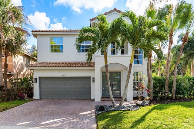 mediterranean / spanish home featuring a garage and a front yard