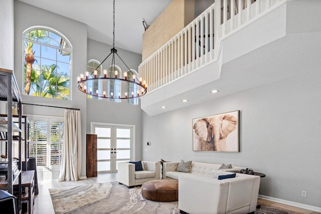 living room featuring a towering ceiling, an inviting chandelier, and french doors