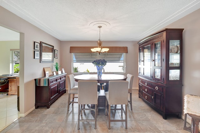 dining area with a healthy amount of sunlight, a textured ceiling, and an inviting chandelier