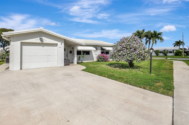 ranch-style home featuring a garage, a front lawn, and central air condition unit