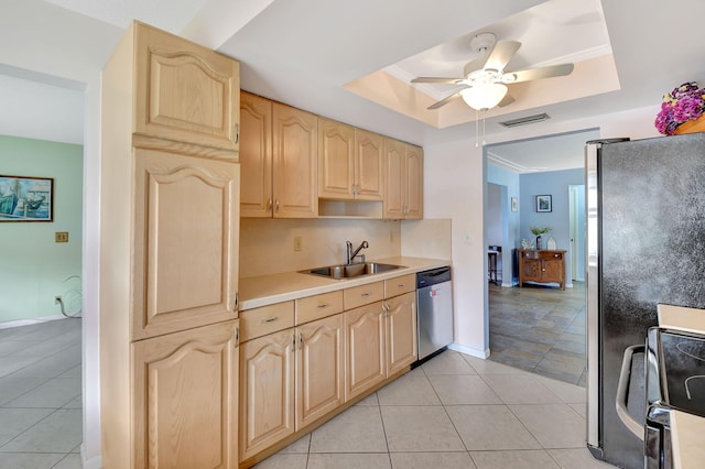 kitchen with sink, light tile patterned floors, appliances with stainless steel finishes, a tray ceiling, and light brown cabinets