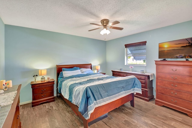 bedroom with hardwood / wood-style flooring, ceiling fan, and a textured ceiling