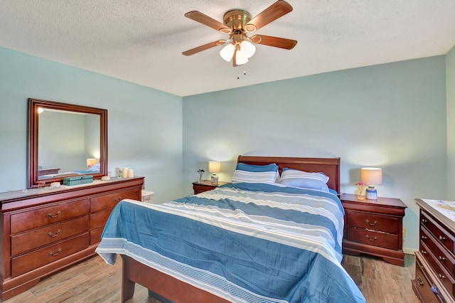 bedroom featuring ceiling fan, light hardwood / wood-style floors, and a textured ceiling