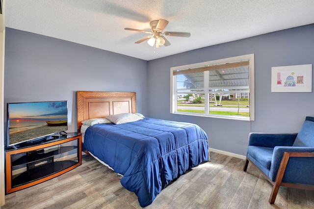 bedroom featuring ceiling fan, wood-type flooring, and a textured ceiling