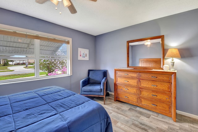 bedroom with ceiling fan, a textured ceiling, and light wood-type flooring