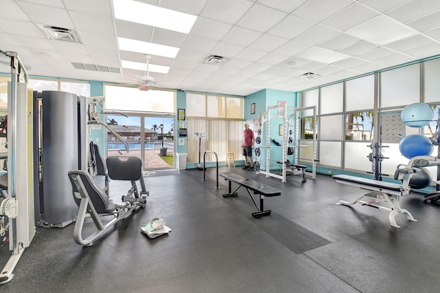 gym with a paneled ceiling and expansive windows