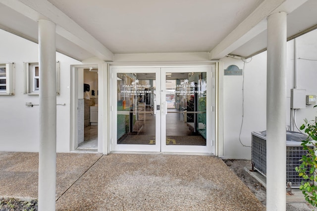 view of exterior entry with french doors, central AC, and a patio