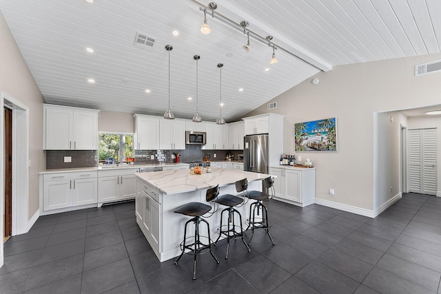 kitchen with decorative light fixtures, a center island, lofted ceiling with beams, stainless steel appliances, and white cabinets