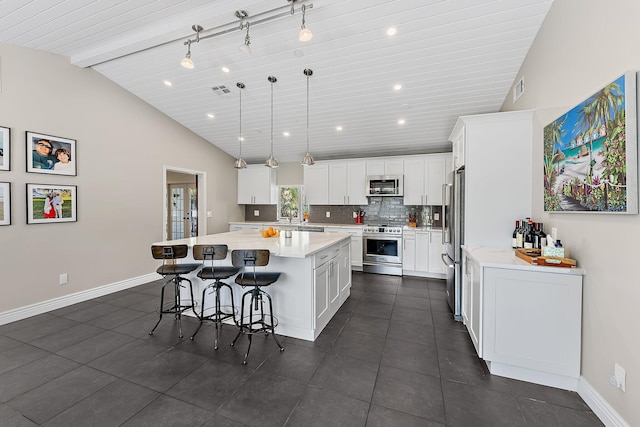 kitchen with pendant lighting, appliances with stainless steel finishes, backsplash, white cabinets, and a kitchen island