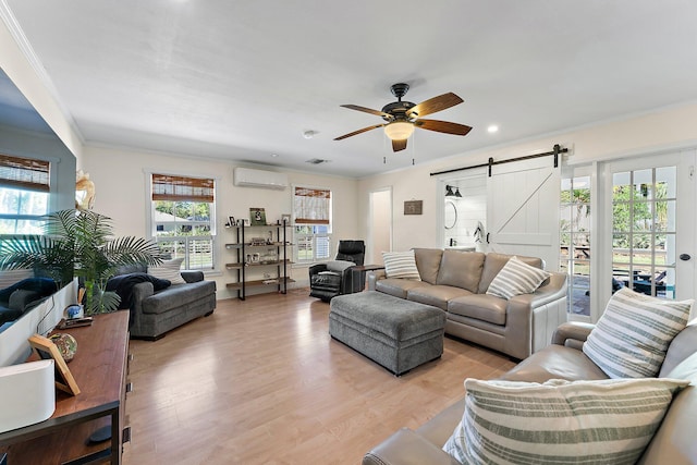 living room with crown molding, a wall mounted AC, light wood-type flooring, ceiling fan, and a barn door