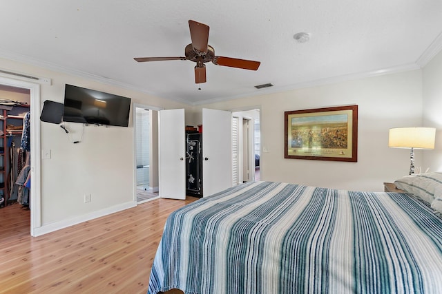 bedroom featuring hardwood / wood-style flooring, ceiling fan, ornamental molding, a walk in closet, and a closet