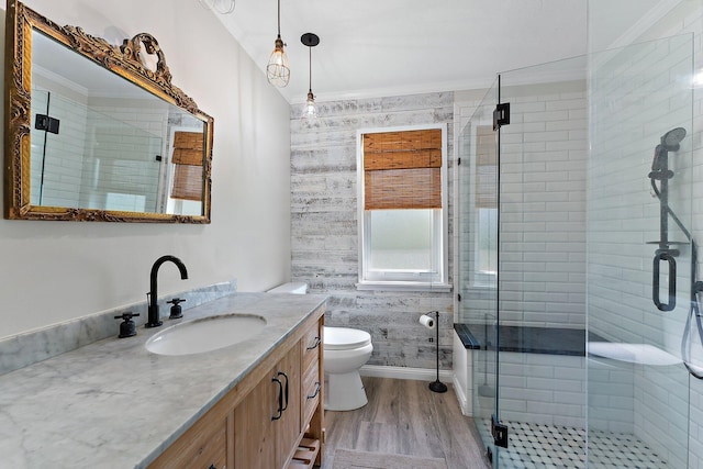 bathroom with wood-type flooring, vanity, ornamental molding, toilet, and a shower with door