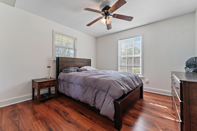 bedroom featuring baseboards, dark wood-type flooring, ceiling fan, and multiple windows