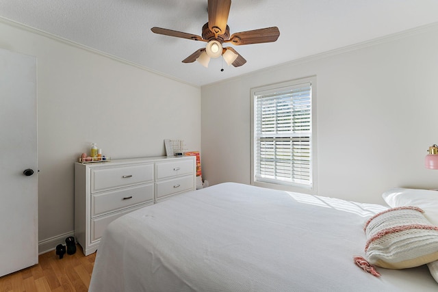 bedroom with light hardwood / wood-style flooring, ornamental molding, and ceiling fan