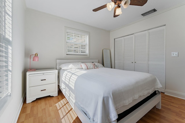 bedroom with ornamental molding, ceiling fan, light hardwood / wood-style floors, and a closet