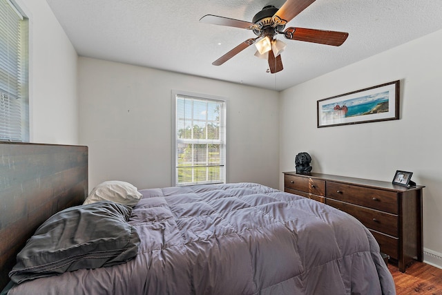 bedroom featuring ceiling fan, hardwood / wood-style floors, and a textured ceiling