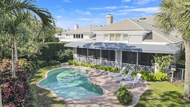 rear view of property featuring a patio, a yard, a fenced in pool, and a sunroom