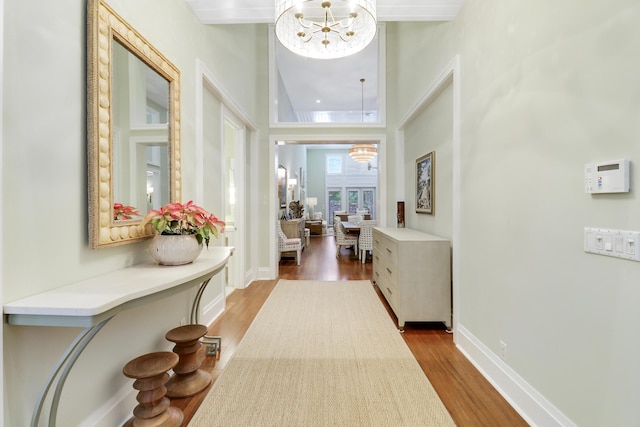 hallway featuring hardwood / wood-style floors, a chandelier, and a high ceiling