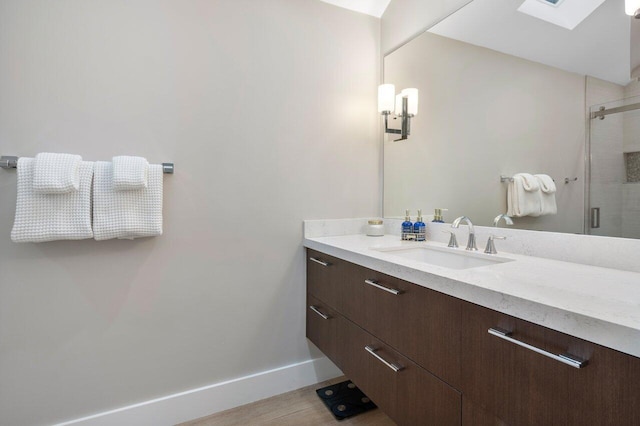 bathroom with hardwood / wood-style flooring, vanity, a skylight, and a shower with door