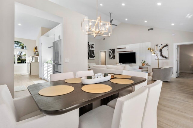 dining area featuring high vaulted ceiling, a notable chandelier, and light hardwood / wood-style floors