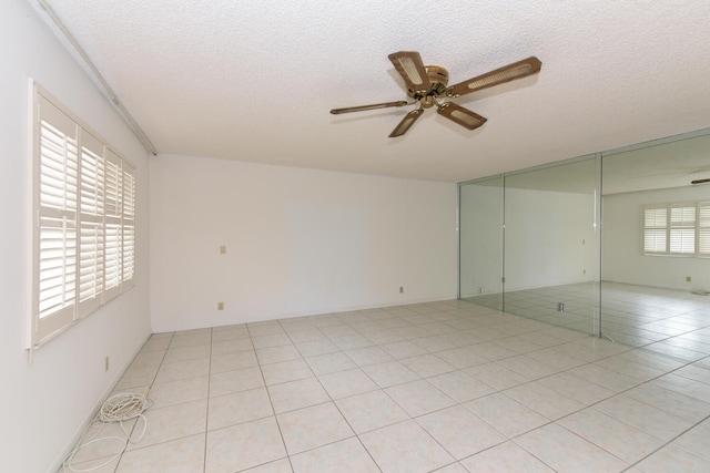 unfurnished room featuring a textured ceiling, ceiling fan, and light tile patterned flooring