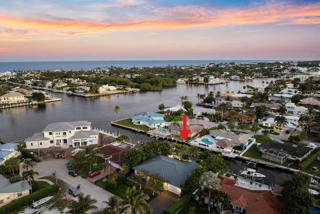 aerial view at dusk featuring a water view