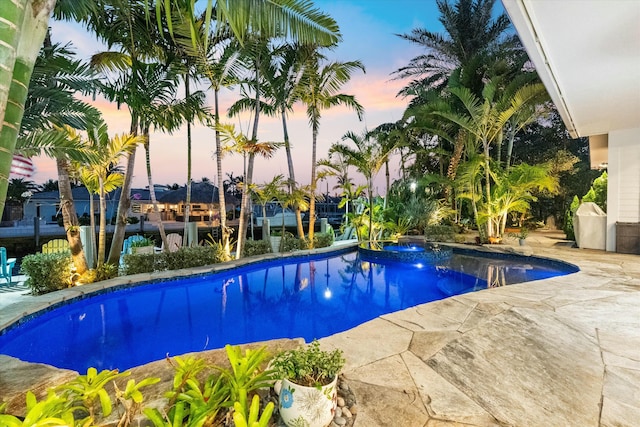 pool at dusk with a patio area