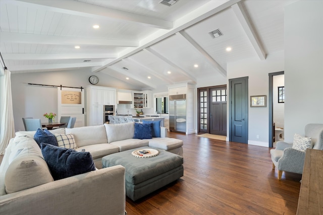 living room featuring lofted ceiling with beams, wood-type flooring, and a barn door