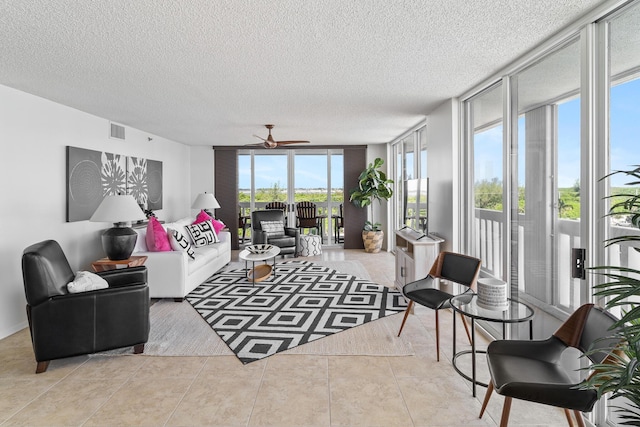 living room with light tile patterned floors, expansive windows, a textured ceiling, and ceiling fan