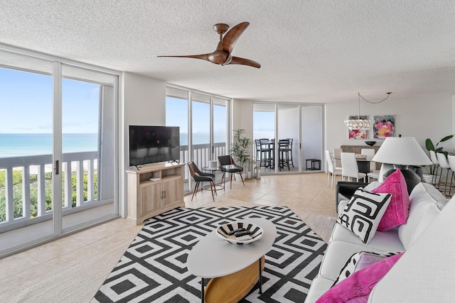 tiled living room with ceiling fan, a healthy amount of sunlight, floor to ceiling windows, and a textured ceiling