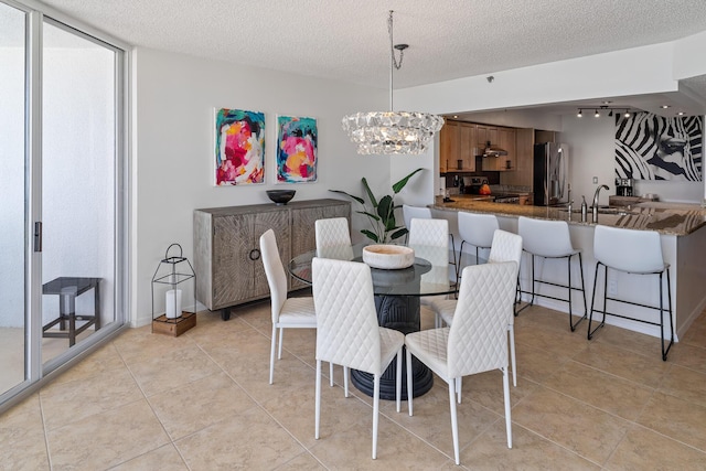 dining area with an inviting chandelier, sink, light tile patterned floors, and a textured ceiling