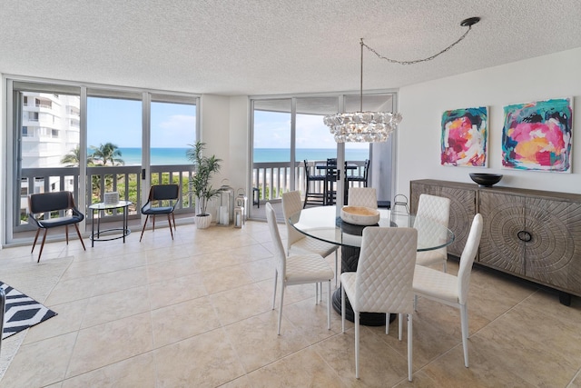 dining area with light tile patterned floors, floor to ceiling windows, a water view, a notable chandelier, and a textured ceiling