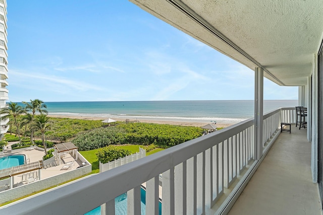 balcony with a water view and a view of the beach