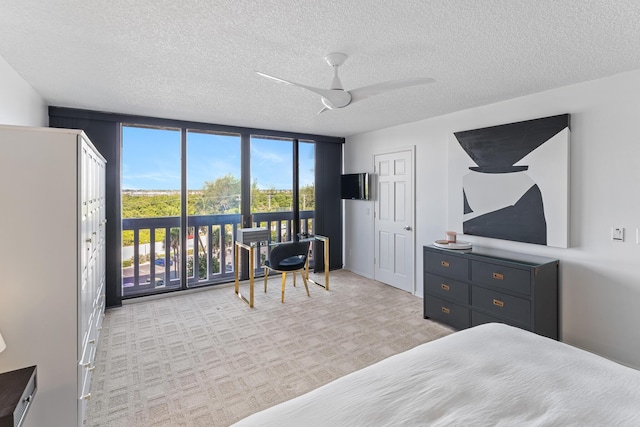 carpeted bedroom featuring ceiling fan, access to outside, a textured ceiling, and a wall of windows