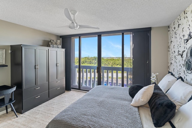 bedroom with ceiling fan, access to outside, light colored carpet, and a textured ceiling