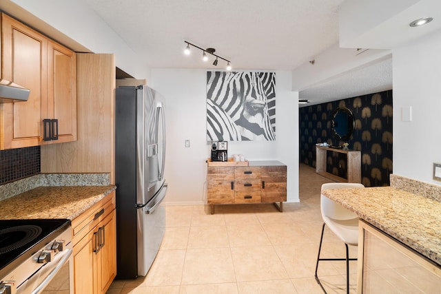 kitchen with a kitchen breakfast bar, appliances with stainless steel finishes, light tile patterned floors, and light stone counters